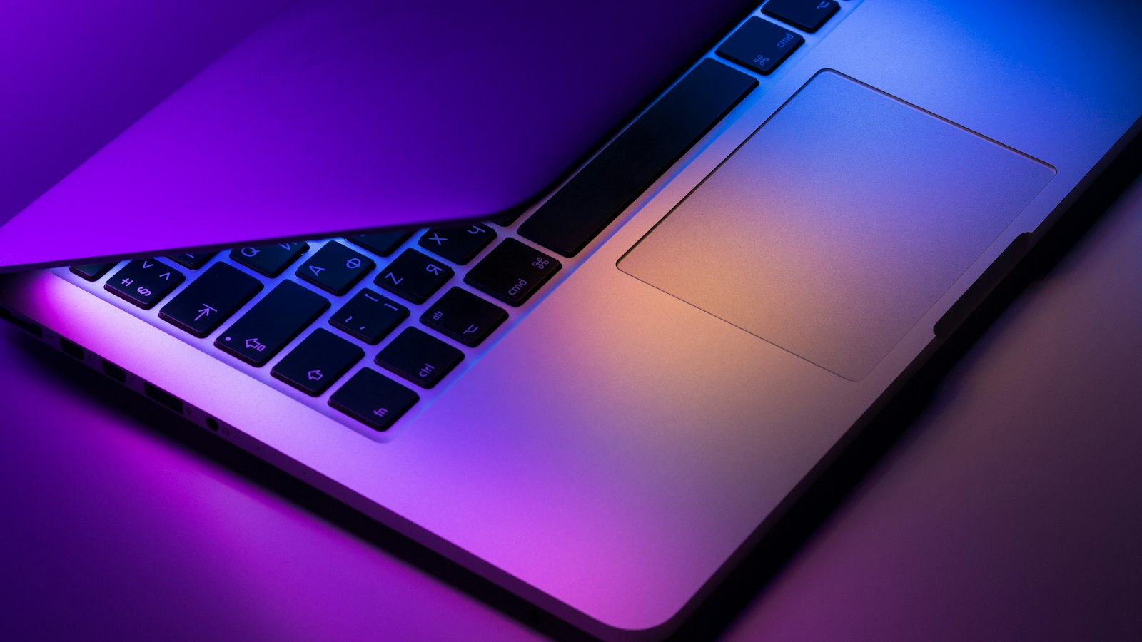 A laptop on a desk in low light with code on the screen
