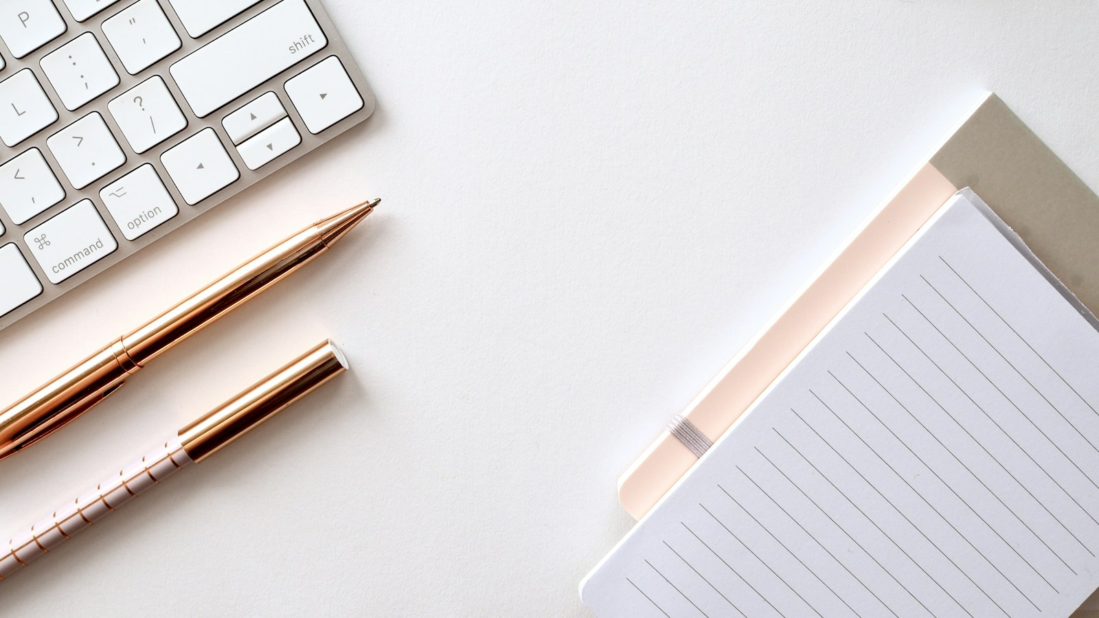 A minimal white keyboard and accessories on a white surface
