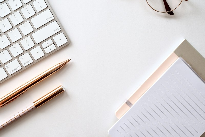 A minimal white keyboard and accessories on a white surface