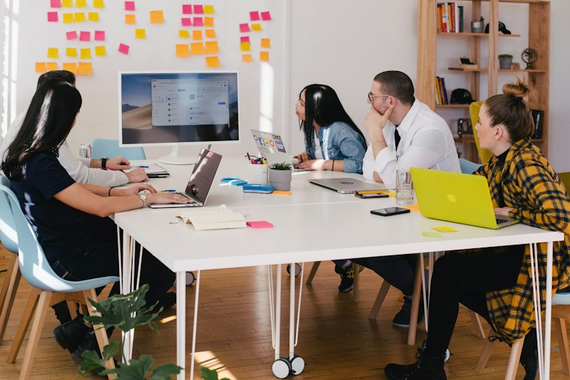 People sitting around a table discussing work with notebooks open